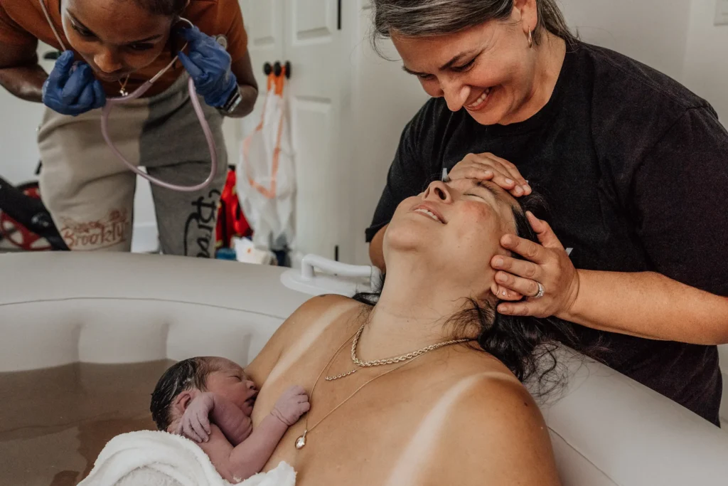 A woman experiences a joyful moment during childbirth with support.