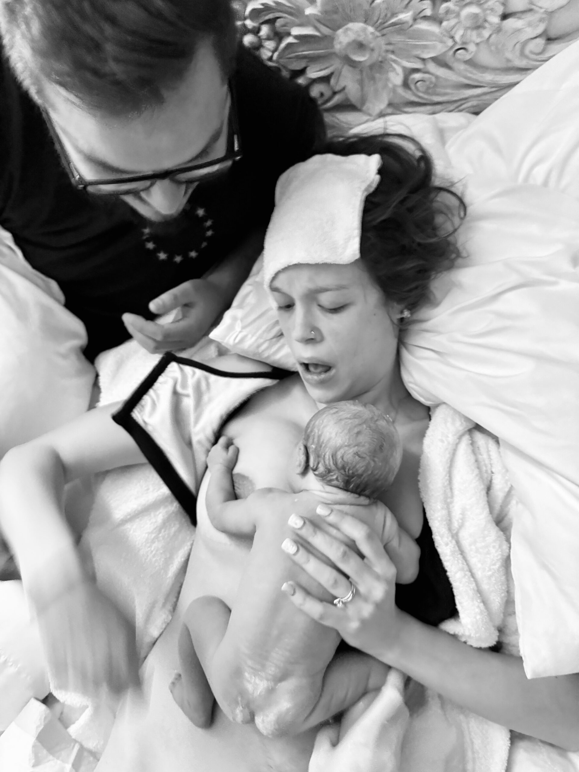 A tender moment of a mother breastfeeding her newborn with a supportive partner beside her.