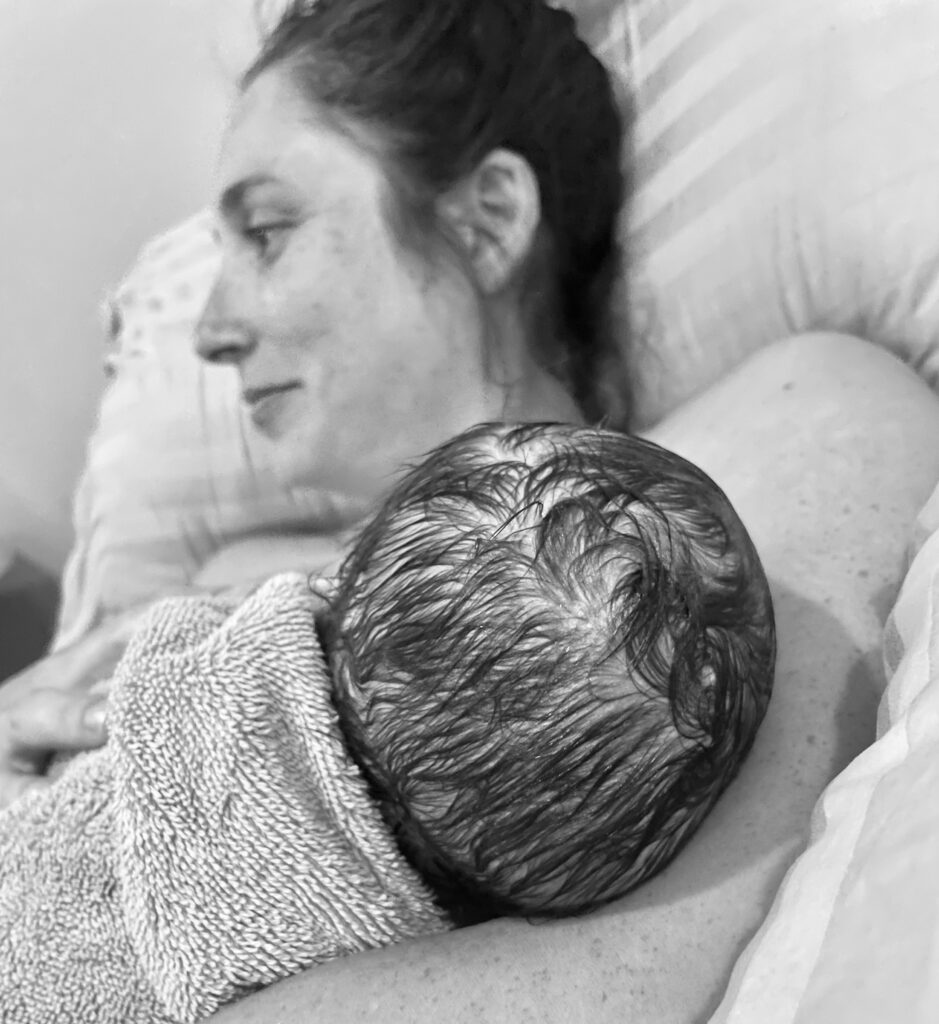 A mother lovingly holds her newborn wrapped in a blanket.