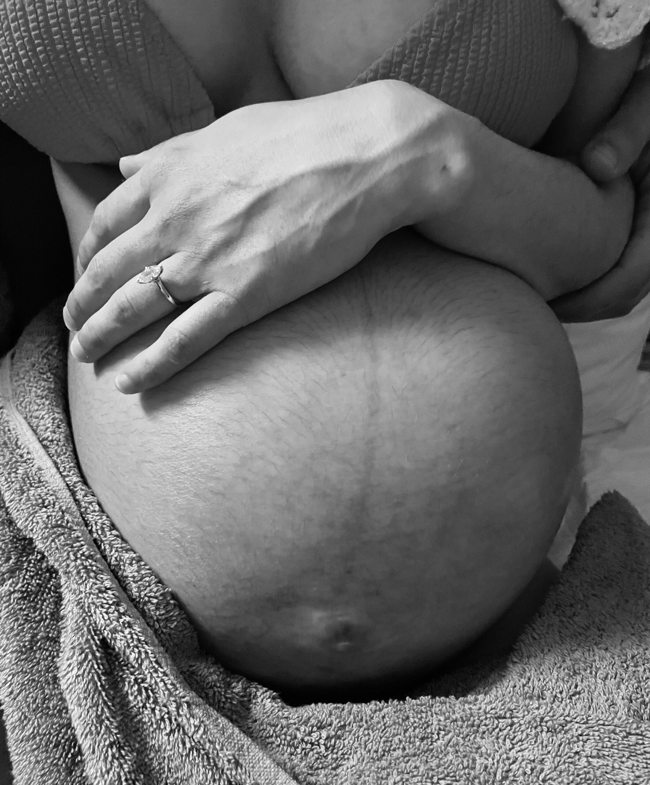 Close-up of hands resting on a pregnant belly with a visible linea nigra.