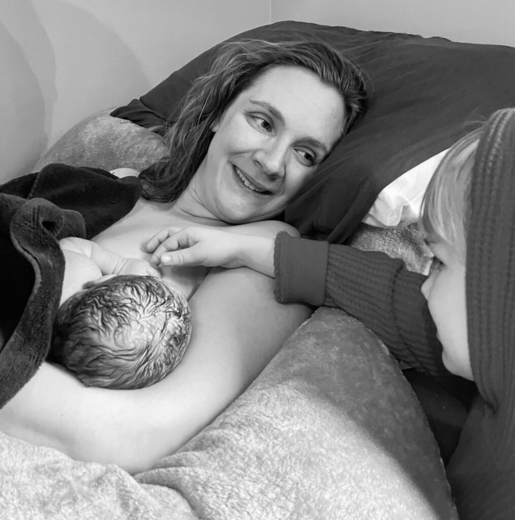 A mother cradles her newborn, sharing a tender moment with a loved one.