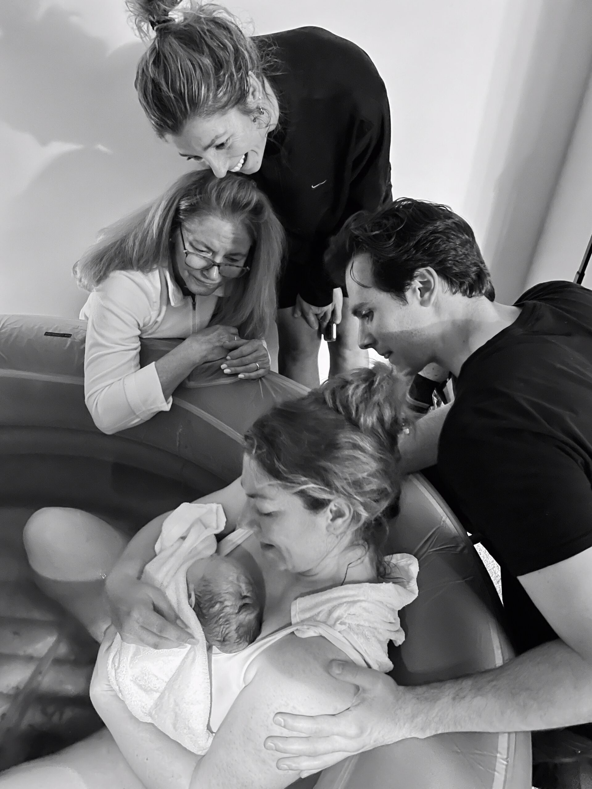 A joyful family admiring their newborn baby at home.