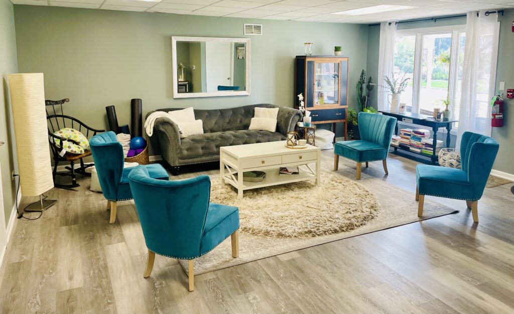 Cozy living room with teal armchairs and a beige sofa around a white coffee table.