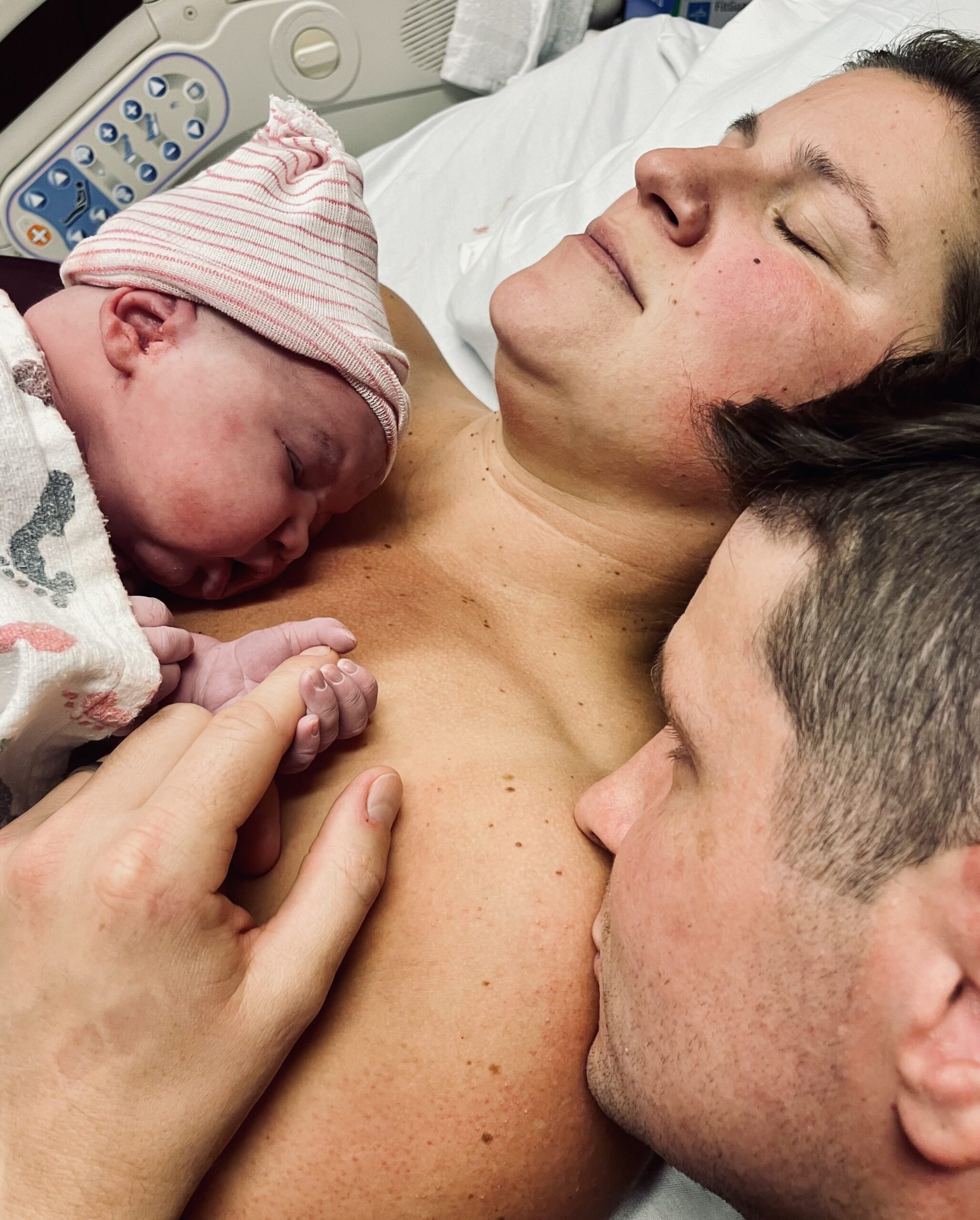 Newborn baby held by parents in a tender moment.