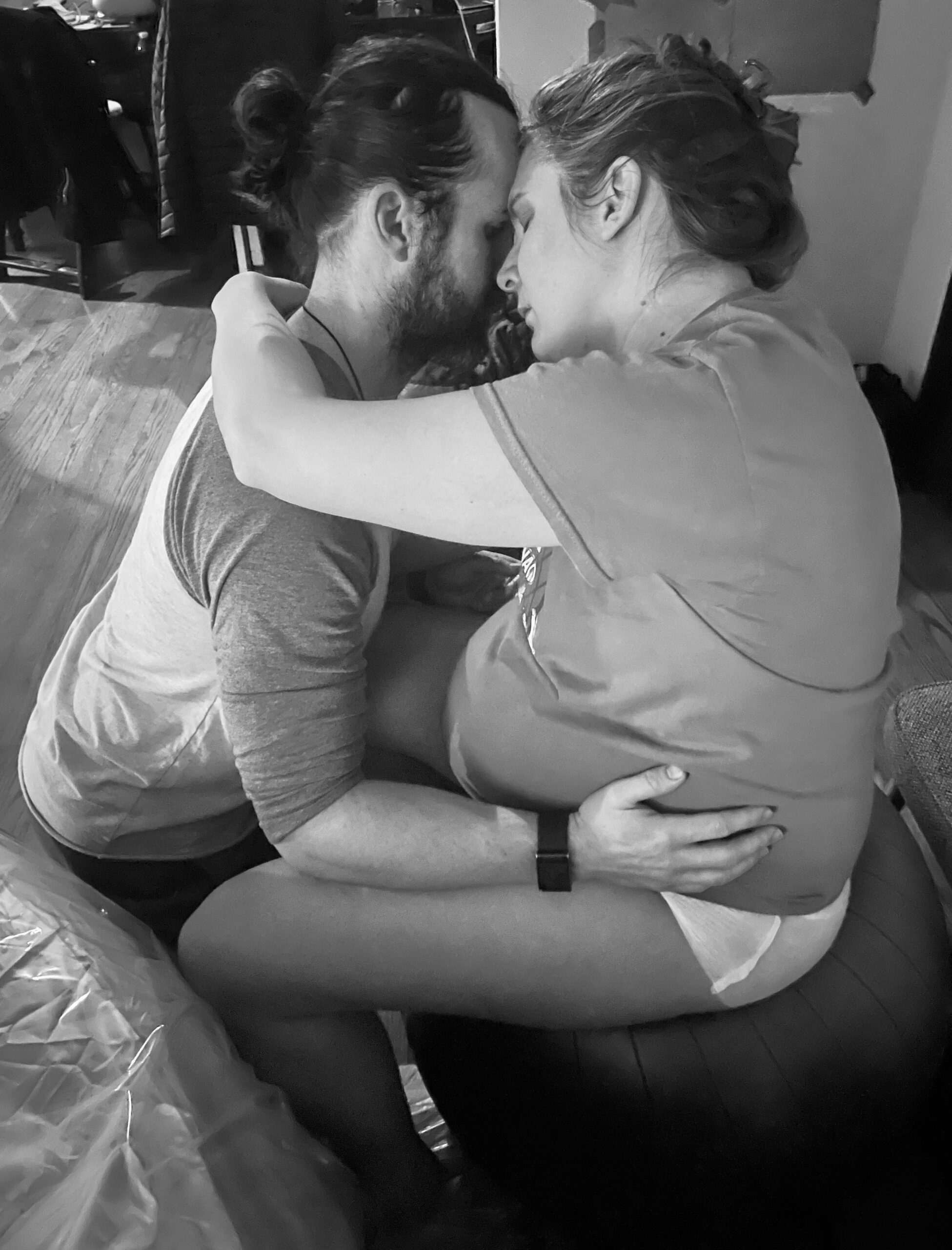 Two men embracing intimately on a bed in black and white.