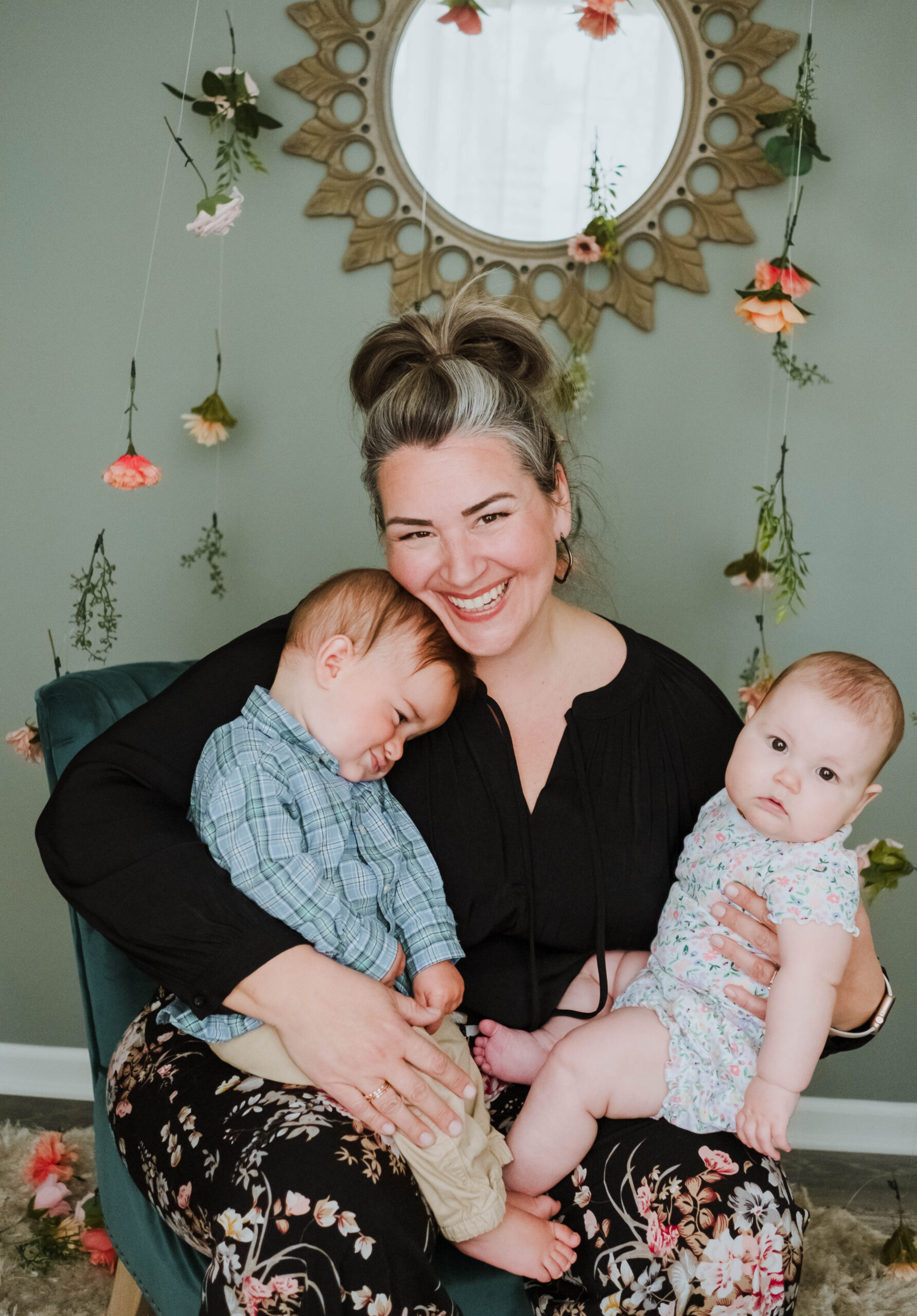 A joyful mother holding two babies, smiling warmly.