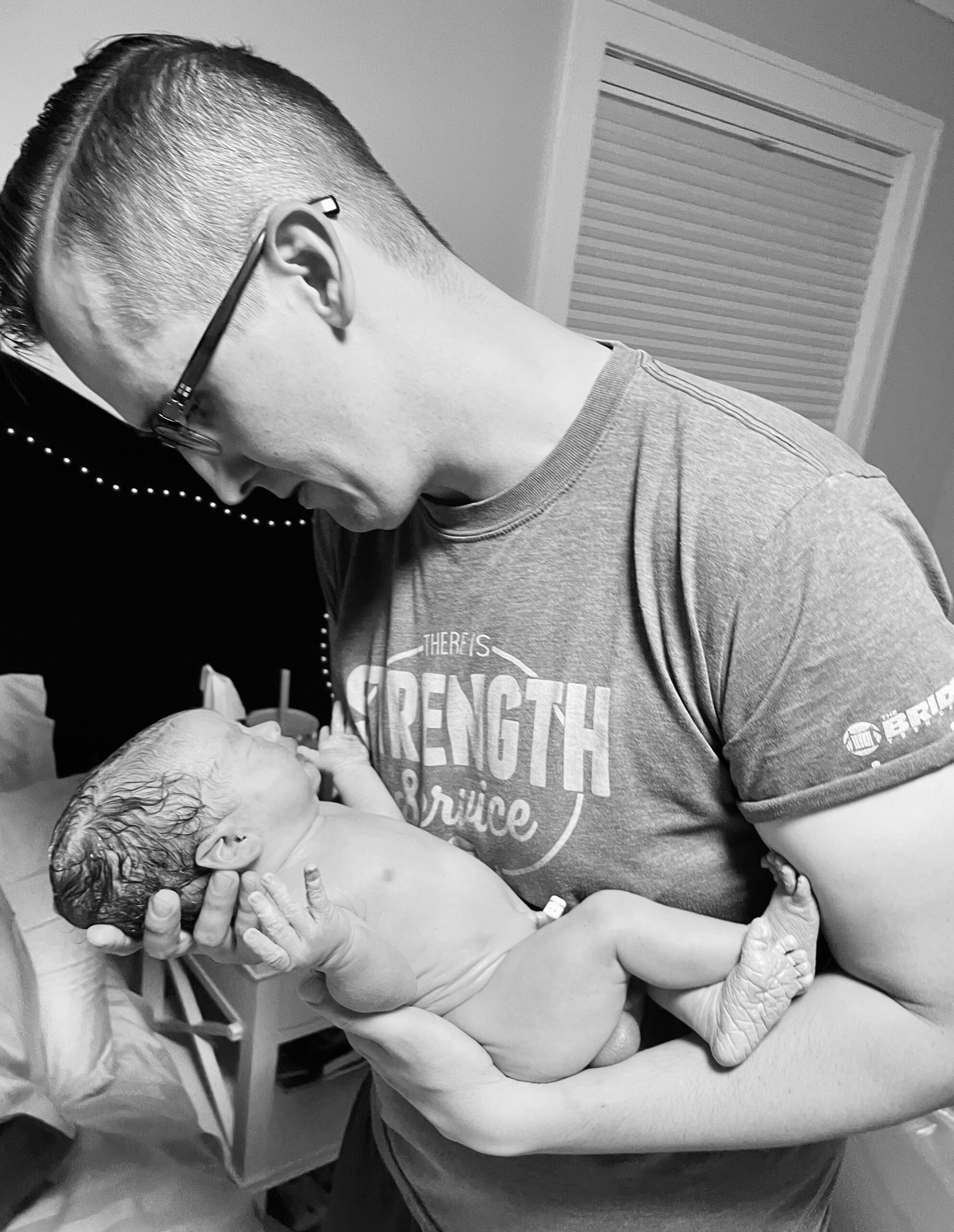 A person tenderly holding a newborn baby in black and white.
