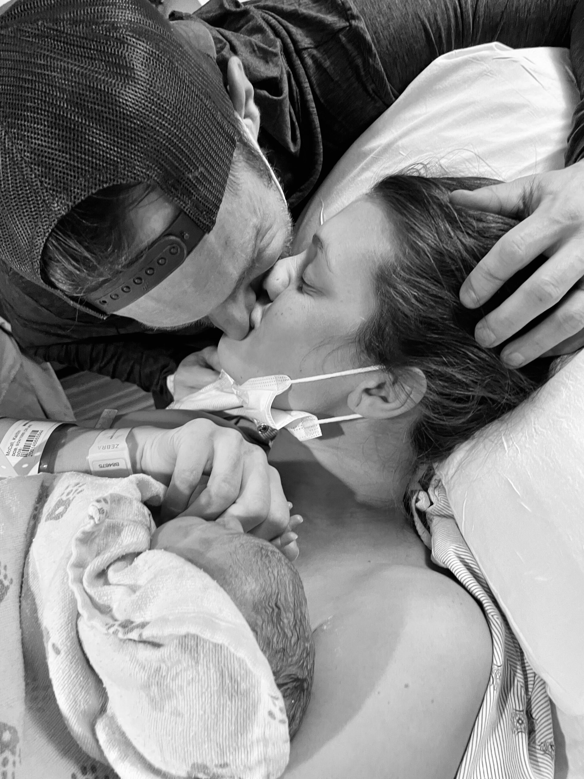 Parents share a tender moment with their newborn baby in black and white.