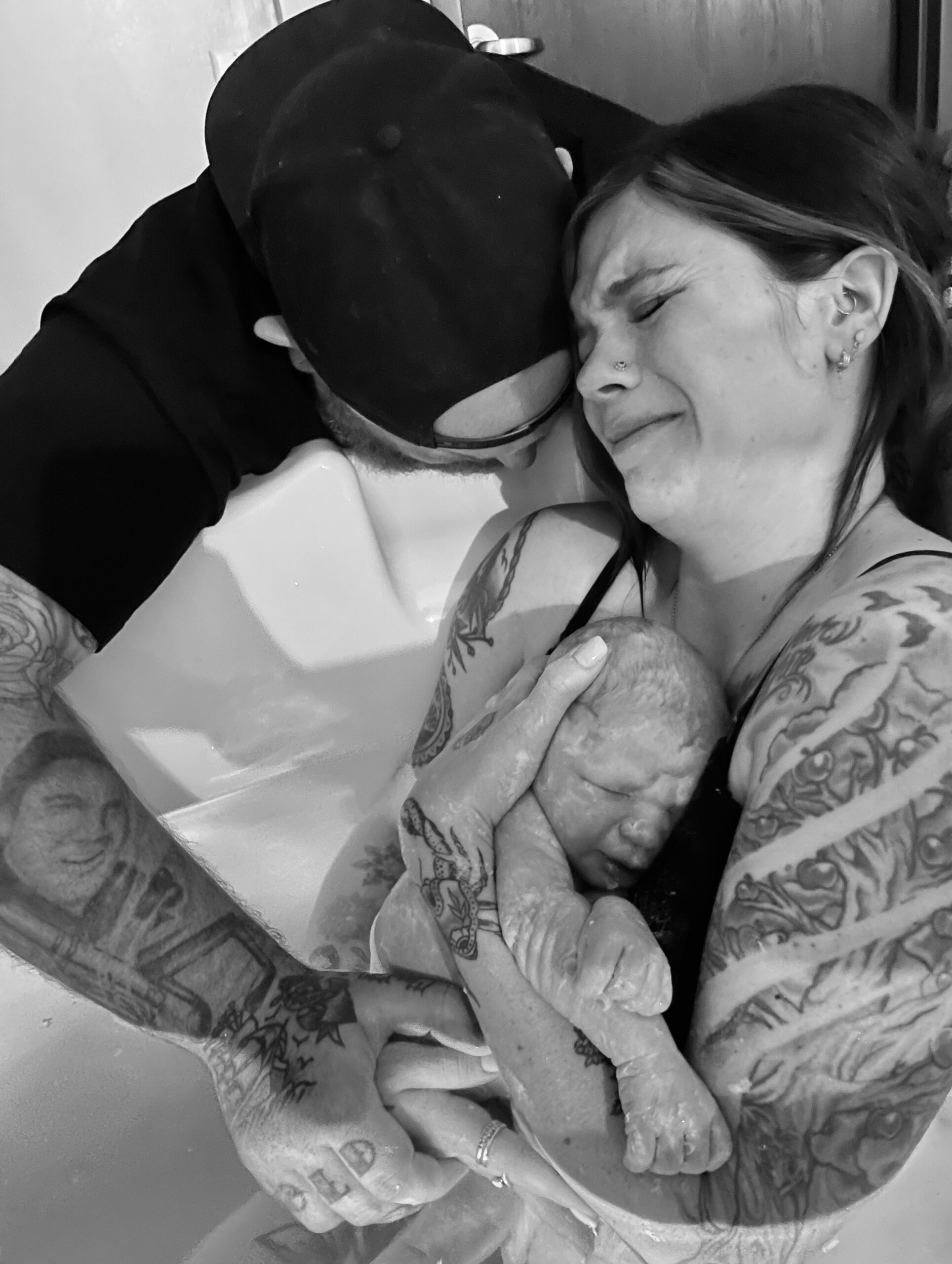 A tattooed couple shares an emotional embrace.