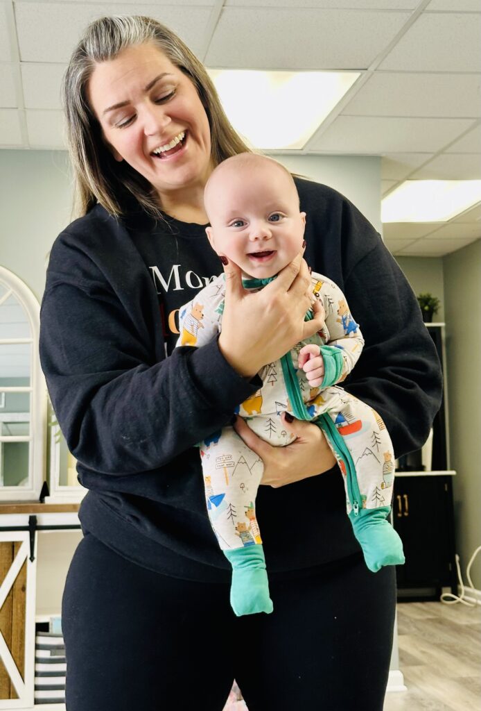 A smiling woman holding a happy baby in a cozy indoor setting.